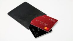 Close-up of a black wallet with a red credit card and a black card inside.