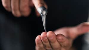 Close-up of a magician performing the Liquify trick with silver liquid metal.