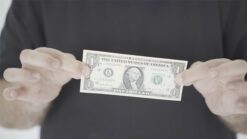 Close-up of a person holding a dollar bill with black lipstick marks on it.