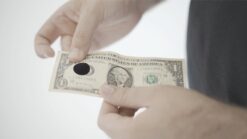 Close-up of a hand performing a magic trick with a dollar bill, emphasizing skill and illusion.