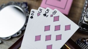 Pink playing cards with reflective surface for magic tricks and illusions.