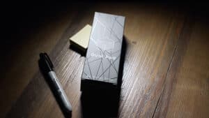 Close-up of the Dual Pad magic trick box and marker on wooden surface.