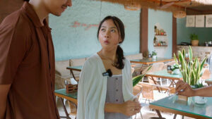 Young woman amazed by a magic card trick in a cozy cafe setting.