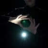 Performer holding glowing orb with light effects, showcasing magic tricks.