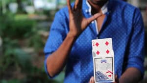 Surya Kumar performing a card magic trick with a 6 of diamonds card.