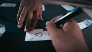 Close-up magic trick with a heart drawing on paper and a smartphone.