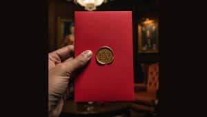 An image of the Elimination Deck, a popular magic trick, held in a person's hand with a red backgrou.