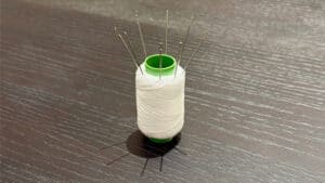 Magic trick with threaded needle and spool for illusion.