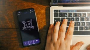 Person performing digital magic trick using smartphone and laptop for entertainment.