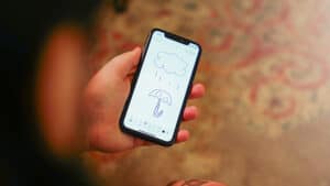 Up of a person holding a smartphone displaying a rain cloud and umbrella drawing.