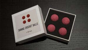 Light pink crochet balls for magic tricks in a black box, perfect for illusions and performances.