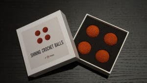 Bright orange crochet balls in a display box for magic tricks.