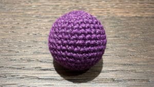 Crochet ball in dark purple with shiny finish, perfect for magic tricks and illusions.
