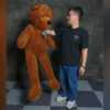 Boy performing teddy bear magic trick with large plush teddy bear.