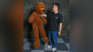 Boy performing teddy bear magic trick with large plush teddy bear.