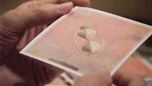 Close-up of a hand performing a magic trick with a spinning top on a card.