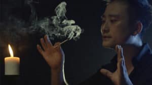 Performer demonstrating fire magic with smoke and flame effects during a magic show.