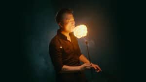 Magician performing fire act with flaming ball during a magic show.