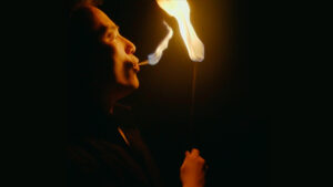 Performer blowing fire during a magic show fire act.
