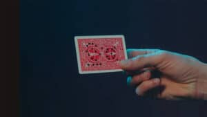 Up of a hand holding a playing card with a red back, part of a magic trick performance.