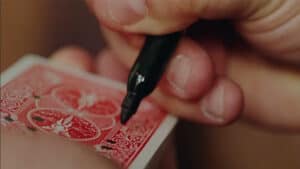 Up of a hand performing a card magic trick with a red-backed playing card.