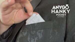 Close-up of hand retrieving a white hanky from a suit pocket for magic trick.
