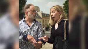 Magician performing a magic trick with a surprised woman outdoors.