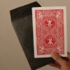 Close-up of a magician's hand holding a red-backed playing card from the "Number 4 Envelope" magic t.