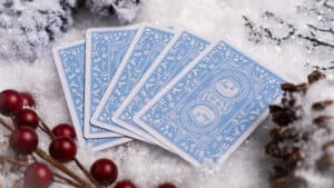 Set of blue Christmas-themed playing cards with snowman design on snowy background.