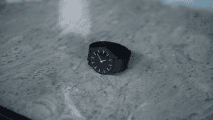 Watch with black strap on textured surface for magic tricks and illusions.