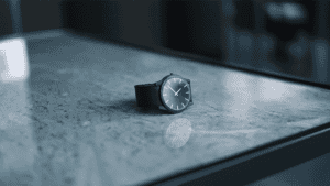 Stylish black wristwatch on a marble surface, showcasing time-telling magic tricks.