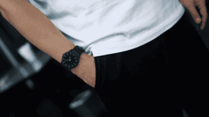 Close-up of a person wearing a black watch and casual white t-shirt.