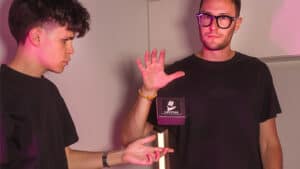 Magician performing levitation trick with audience in background.