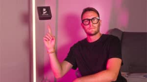 Magician performing levitation trick with logo in background.