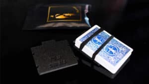 Close-up of a sleek card holder with playing cards and magic accessories on a black surface.