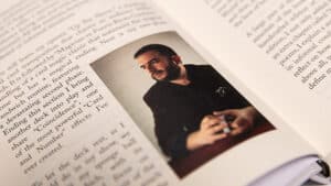 Close-up of a man performing a magic trick with cards in a book setting.