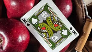 Close-up of Johnny Appleseed playing card from Midnight Cards deck with apples in background.