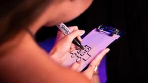 Close-up of a person writing on a clipboard with a marker, showcasing a magic trick.