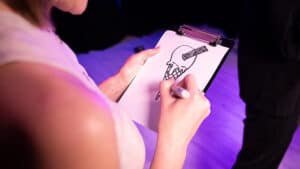 Person drawing a magic trick on a clipboard during a performance.