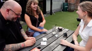 People enjoying a magic cube trick at an outdoor gathering.