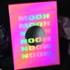 Bright pink holographic Moon playing cards with bold "MOON" text in neon colors.