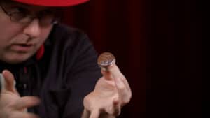 Magician performing a coin trick with a coin balanced on his finger.
