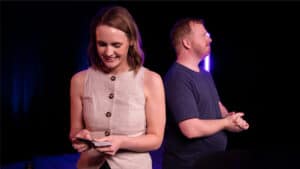 Magician performing a card trick on stage with an audience.