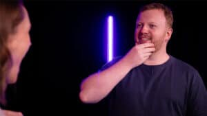Man performing a mesmerizing HEX magic trick with glowing light in dark setting.