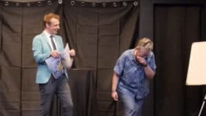 Chris Philpott performing a magic trick on stage during Odyssey 2 event.