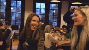 Two women performing magic tricks in a lively indoor setting.