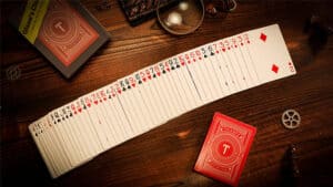 Close-up of a long deck of playing cards with red backs, spread out on a wooden table for a magic tr.