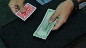 Close-up of a card and dollar bill for magic trick performance.