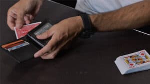 Up of a magician performing a card trick with a deck of cards and a wallet.