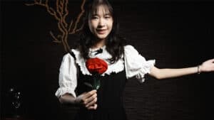 Young woman holding a red rose in a magic-themed fantasy setting.